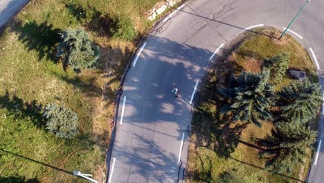 imágenes de drones desde arriba de un hombre patinando cuesta abajo en un camino muy sinuoso con muchos giros, filmado en la noche con un brillo dorado en la imagen