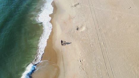 vista de pájaro de un ciclista montando en la playa a lo largo de la costa de virginia