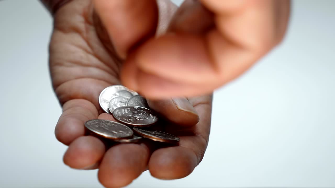 un hombre se toma su tiempo examinando una pequeña cosa en su mano, tratando de encontrar una moneda correcta