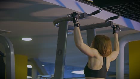 woman doing pull-ups in gym