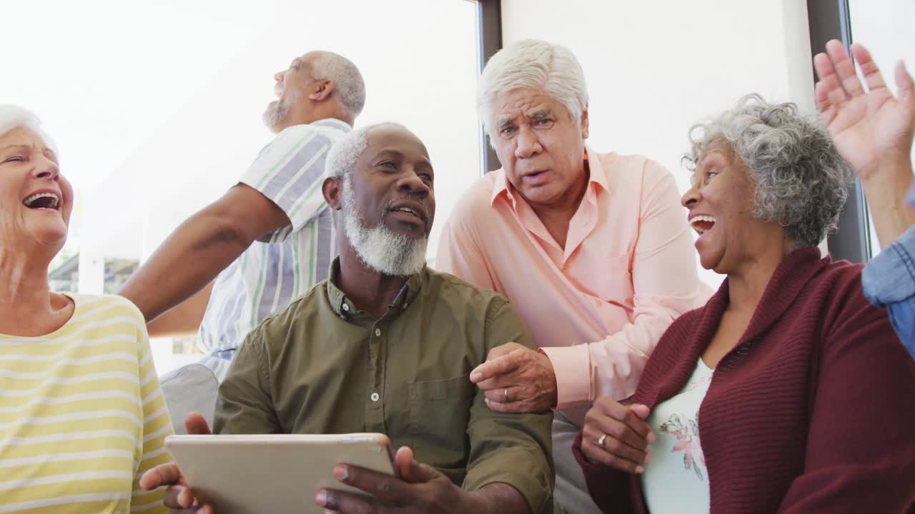 personas mayores felices y diversas hablando y usando computadoras portátiles en el hogar de ancianos