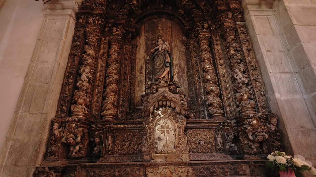 Altare barocco elaborato con statua e intagli floreali all'interno di una chiesa.