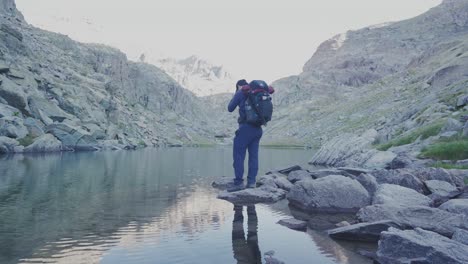 a solo hiker stand alone by the lake, and walk away