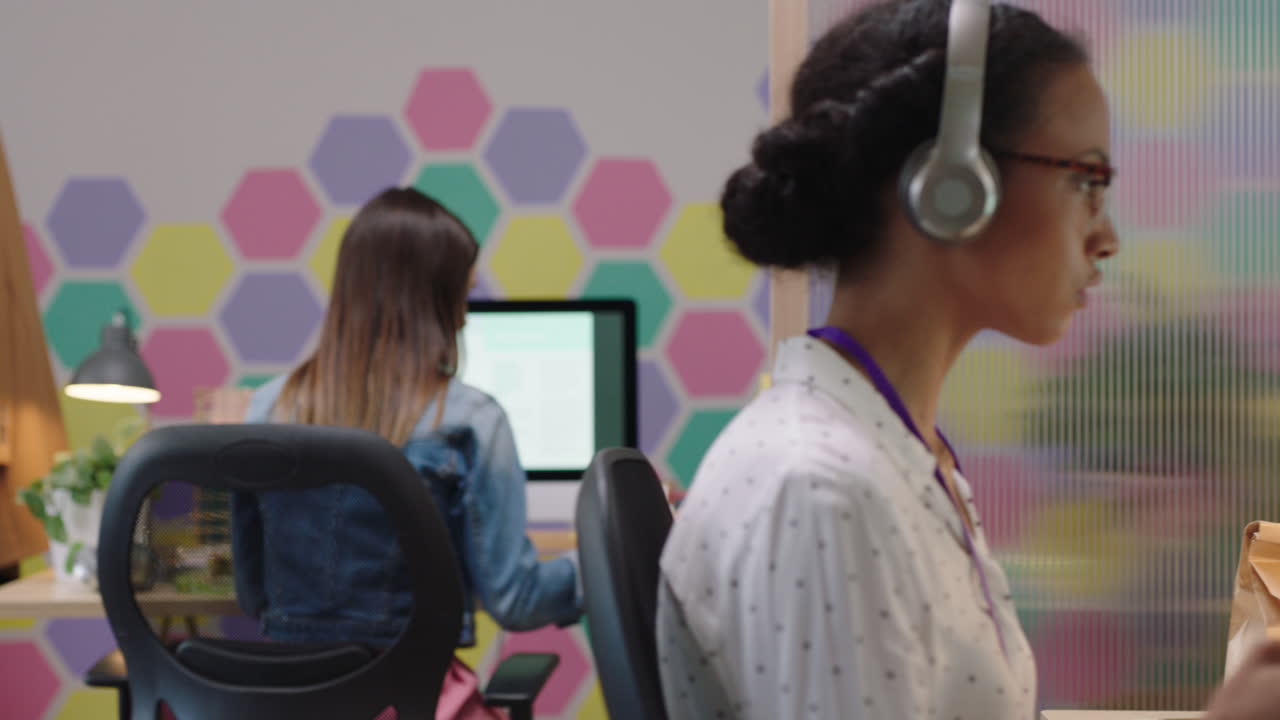 joven mujer de negocios de raza mixta usando la computadora navegando en línea trabajando en un proyecto de redes escuchando música disfrutando de la oficina de inicio de moda
