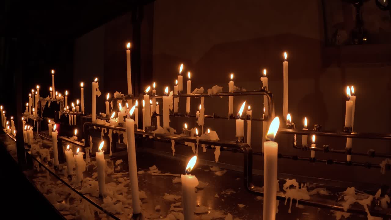 Soft flickering church candles glowing, warm light in a dark environment