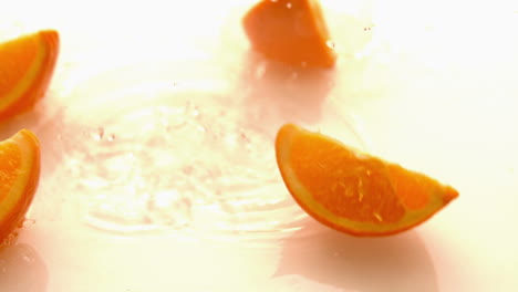 Pieces-of-orange-falling-on-white-wet-surface