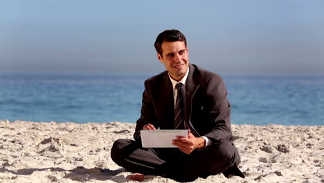 Unstressed-businessman-using-tablet-pc-on-the-beach