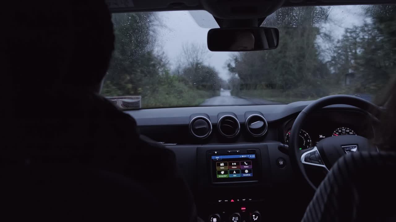 Two women driving on a bumpy road in Ireland. Rain hitting the windscreen. Handheld camera shot.