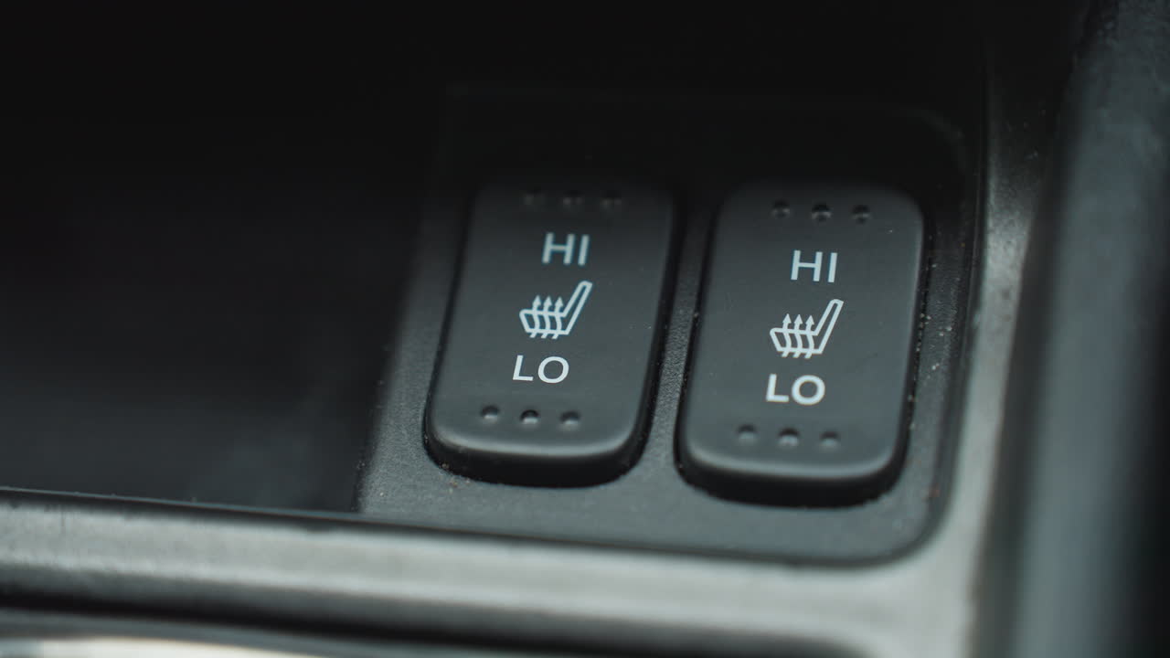 Close up of person turning off seat AC button on car console showing finger interaction with red indicator light HI LO icons press action focusing on plastic surface and modern cabin control design