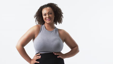 young biracial plus size woman with curly hair standing with hands on hips