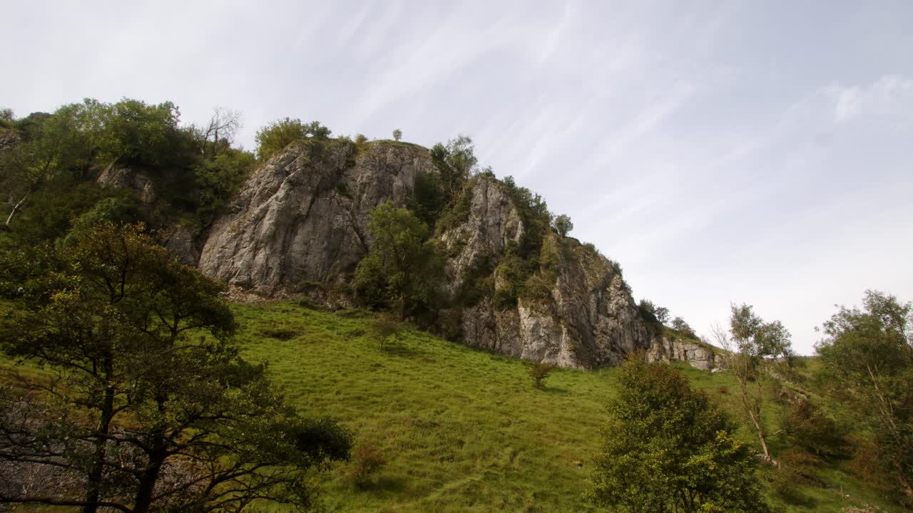 Ampia veduta panoramica che risale il percorso di Dove Dale, di un affioramento roccioso, uno sperone e una parete di roccia