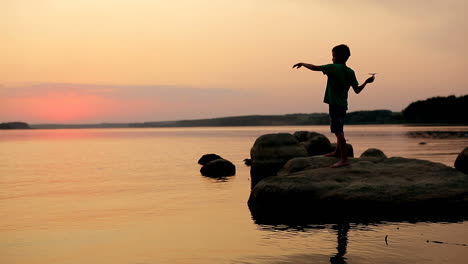 boy playing on beach at sunset. silhouette of happy children playing on beach at sunset