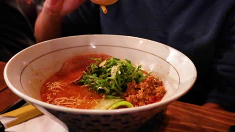 person savoring ramen with toppings and broth