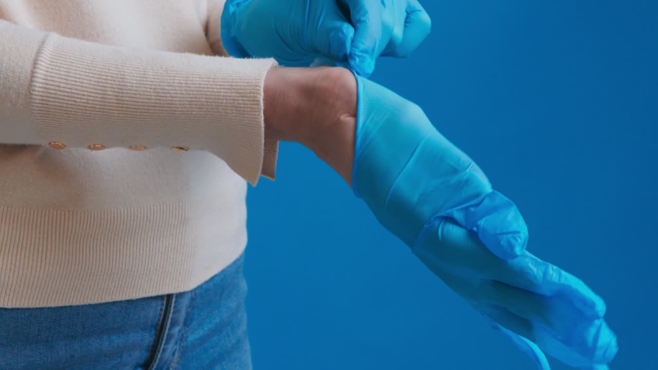 человек, надевающий синие перчатки