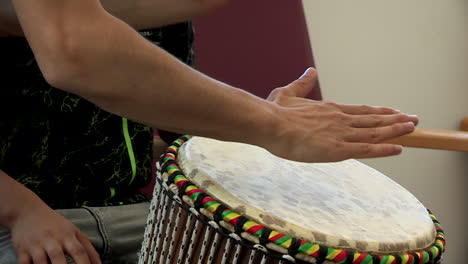 close-up of teacher and student hands playing djembe