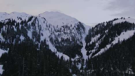 Backwards-tilt-up-drone-shot-of-with-snow-covered-Mount-Baker-in-winter-time