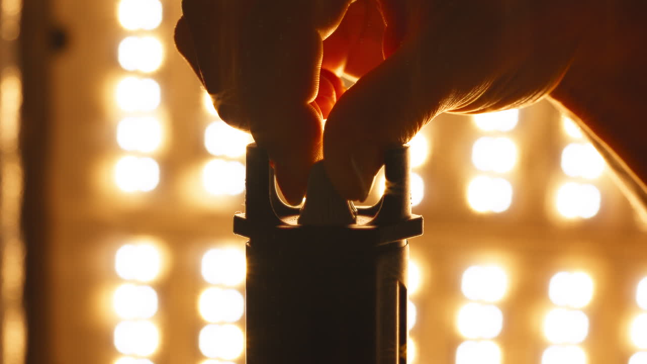 A Hand Adjusts the Lamp, Triggering a Warm Glow From the Lights Behind - Close Up