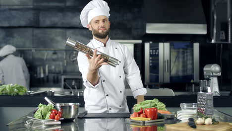 chef posando en un restaurante de cocina. chef calentándose con pepperbox en el lugar de trabajo.
