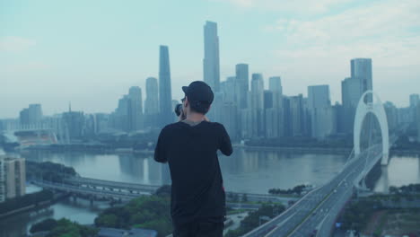 open shot of young asian photographer capturing urban city downtown from a rooftop in the early morning