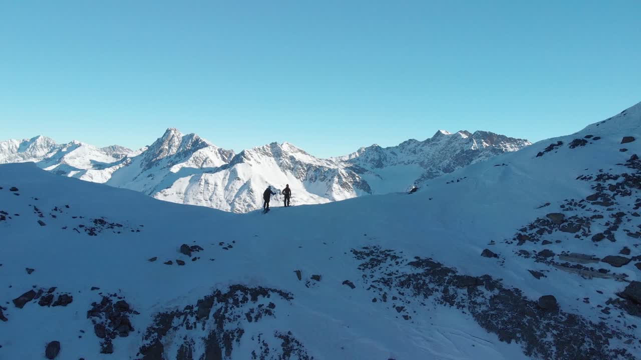 두 명의 스키 하이커를 따라가는 공중 전망, 산 정상에 도달, 오스트리아의 햇살, 겨울날 - 상승, 드론 샷