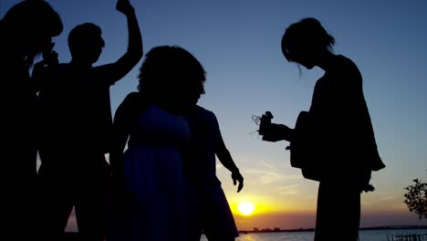 silueta de amigos disfrutando de la puesta de sol en la playa