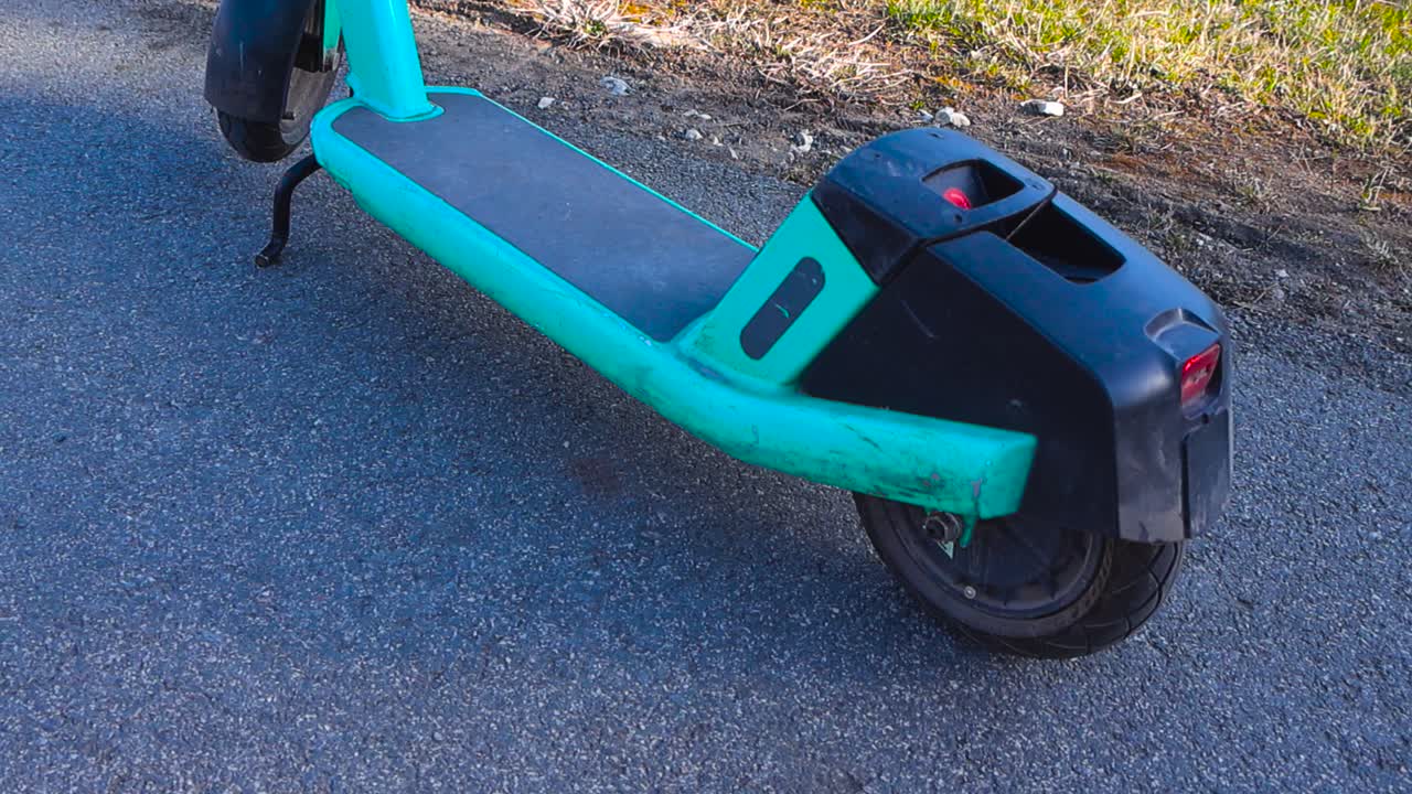 Modern electric rental scooter parked on an asphalt road in a city, providing an eco friendly and convenient urban mobility sharing service for short distance transportation on a sunny day