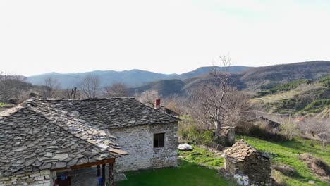 small village house with stone tiles on the roof and chimney overlooking mountains and fields