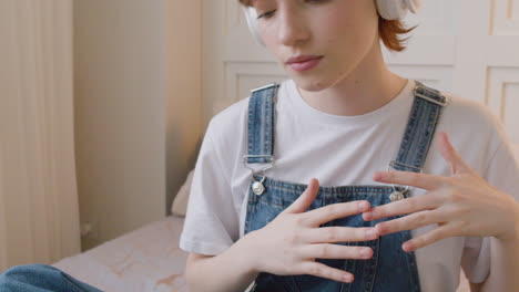 ベッドに座ってヘッドフォンを着用し、音楽のビートに合わせて頭を動かしている女の子の接写1