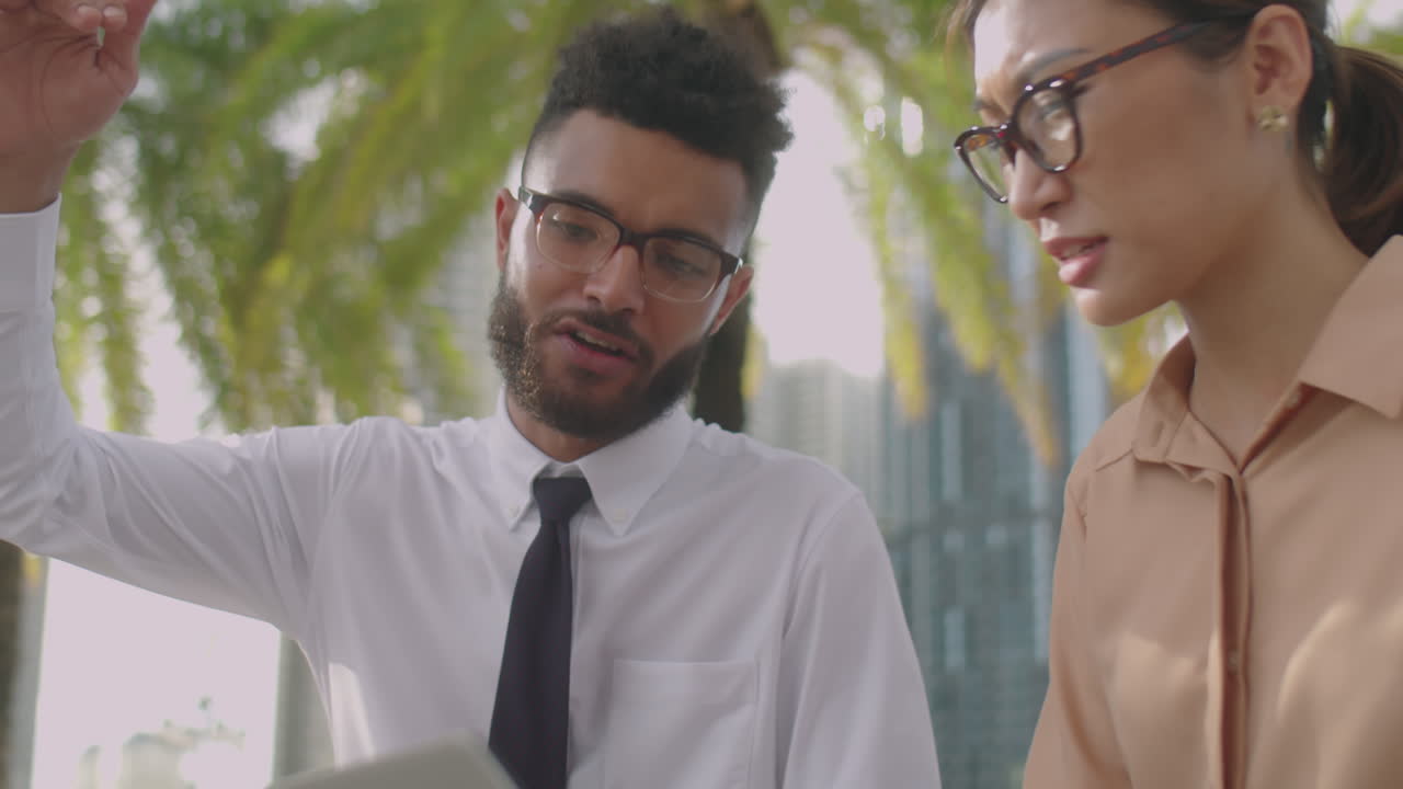 Coworkers Using Laptop and Talking Outdoors in City