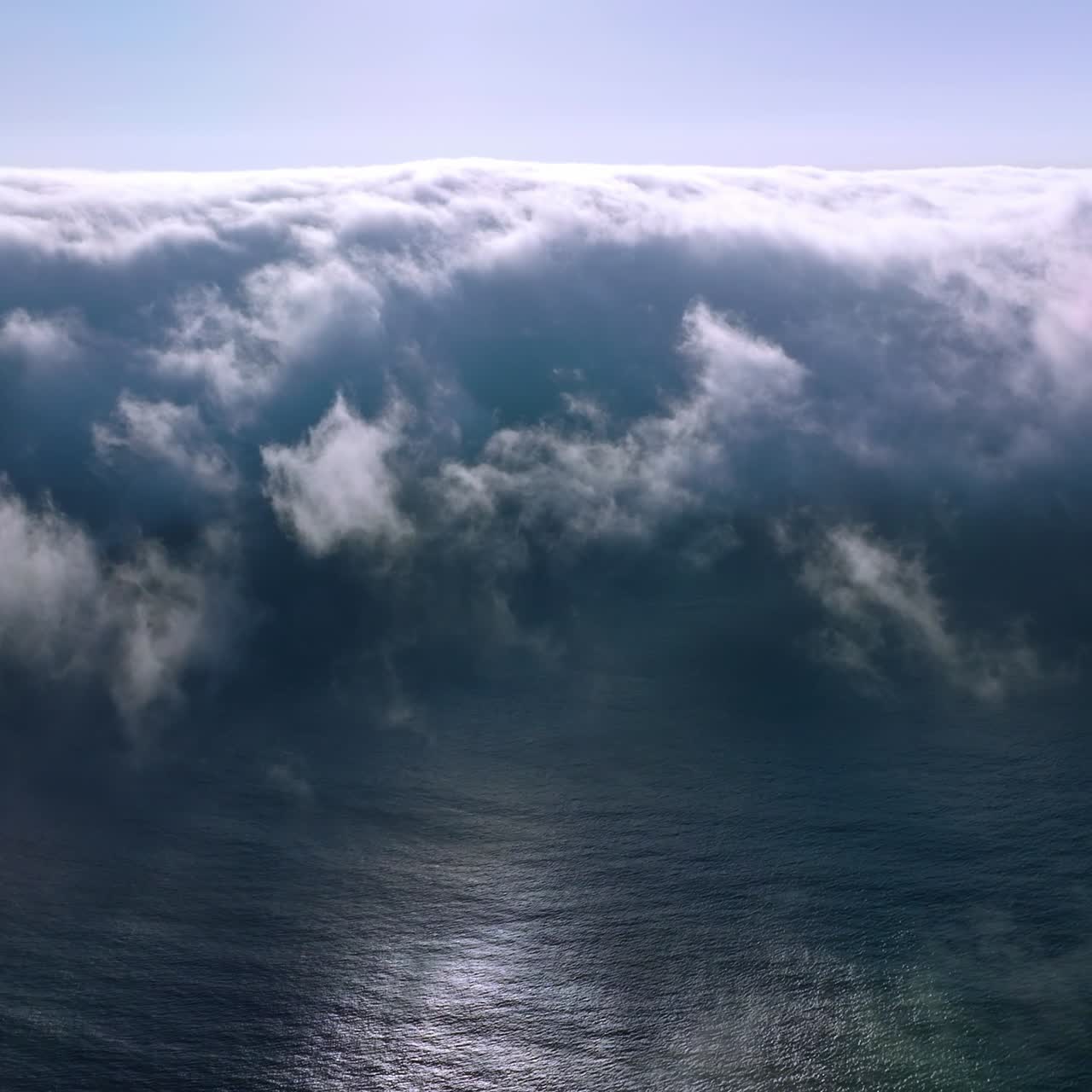 Thick white fog spreading to the coastline from water. Amazing cloudscape of haze on sunny summer day. Aerial view