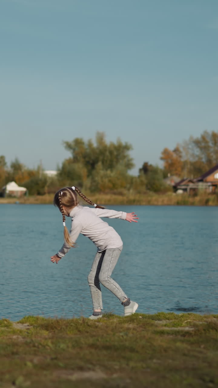 niña preescolar activa lanza una pequeña piedra al agua girando en la playa verde. recreación en la naturaleza en un día cálido y soleado. el niño se divierte cerca del estanque