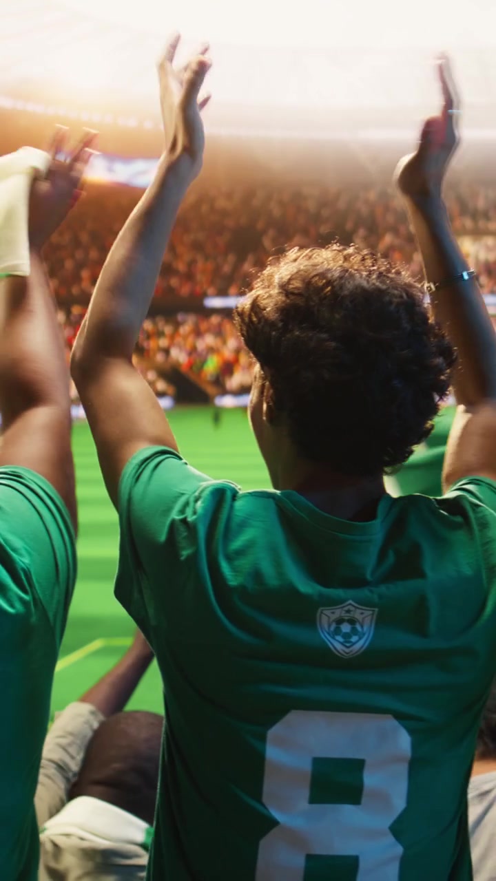 Video vertical: Primer plano de aficionados al fútbol aplaudiendo en estadio abarrotado durante el día del partido.