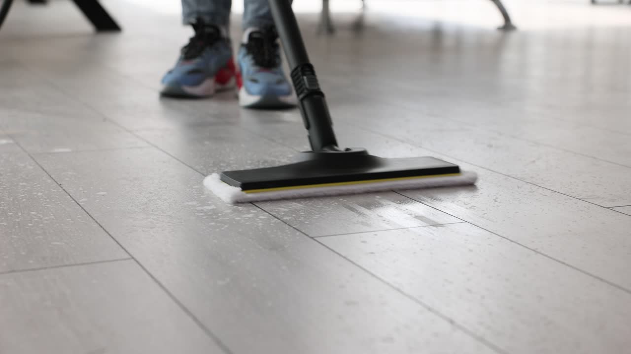 Person mopping or steam cleaning a wet floor