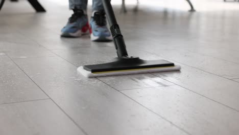 person mopping or steam cleaning a wet floor