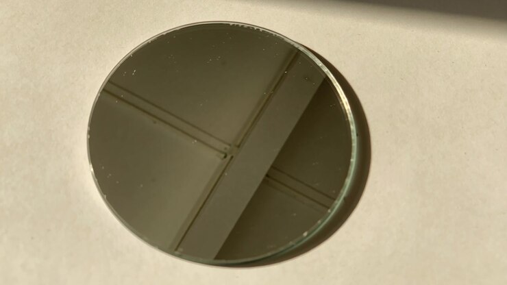 Shifting mirror disc on off-white sheet on table, reflecting ceiling beams while light shifting
