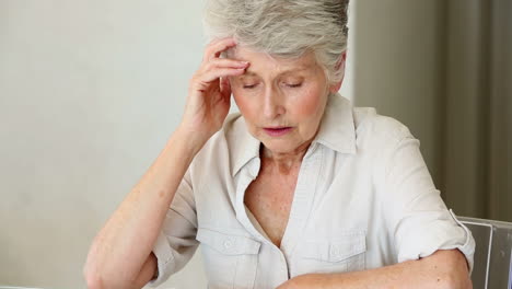 Senior-woman-sitting-at-table-working-out-bills