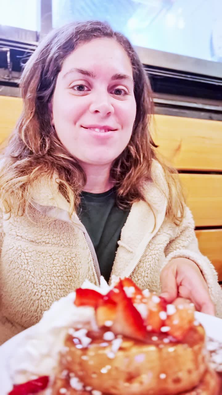 Mujer disfrutando de deliciosos panqueques con fresas y crema batida