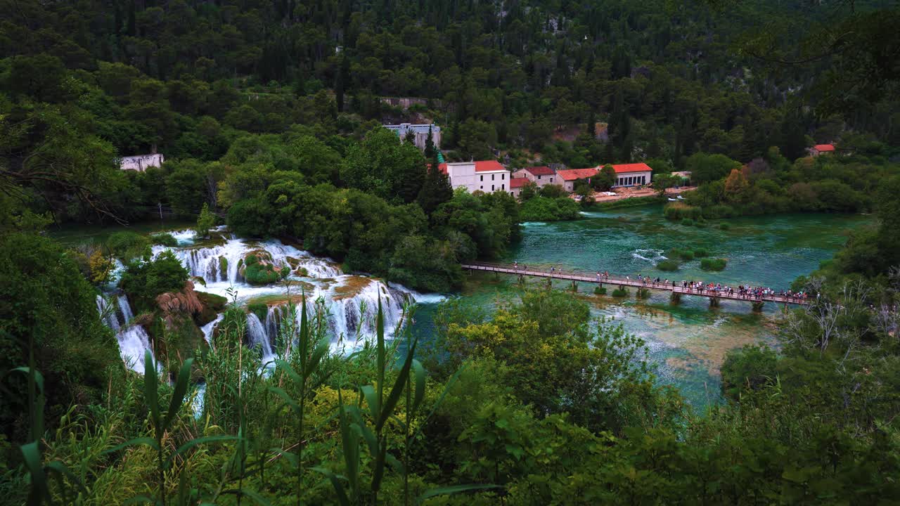 Scenic view of turquoise lakes and cascades in Krka National Park during spring with tourists crossing a bridge