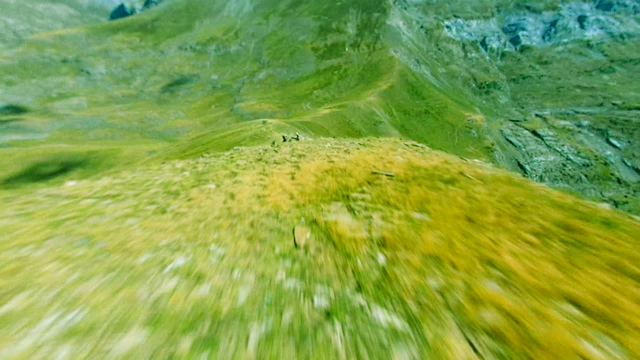 фпв дрон ныряет на вершине гор, закрывает скалы и зеленые деревья