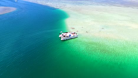 tour boat anchored at the kaneohe sandbar with tourists swimming in shallow water