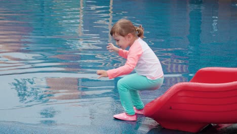 3-year-old little girl is riding a slide in an outdoor water park playground - slow motion