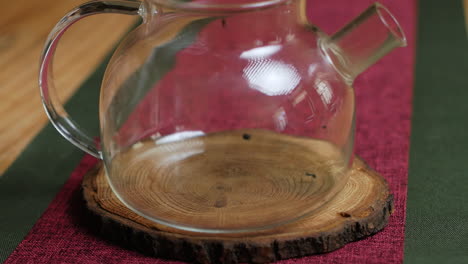 pouring tea leaves into a glass teapot