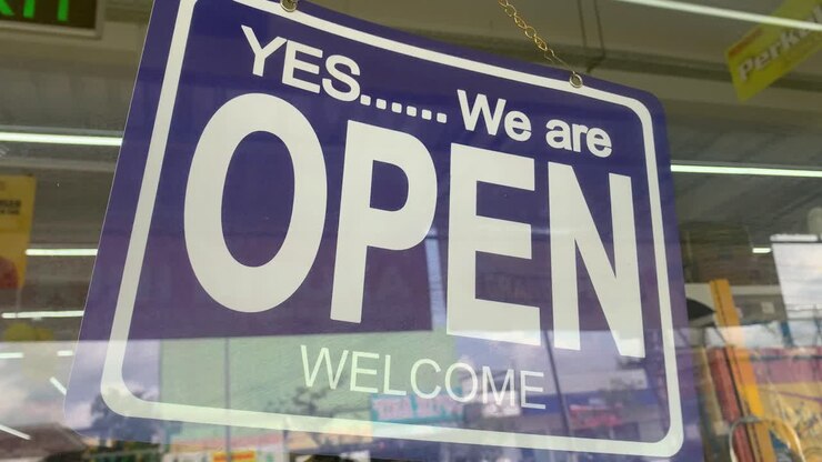 An open sign hanging on the front door of the supermarket