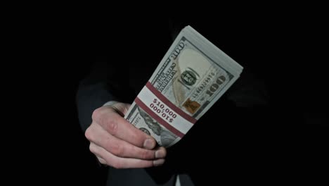 stack of 10000 american dollars in bundle in male hands on black background