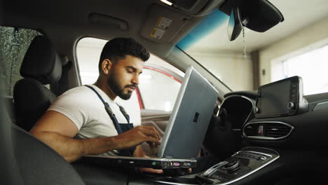 mecánico trabajando en diagnósticos de automóviles usando una computadora portátil
