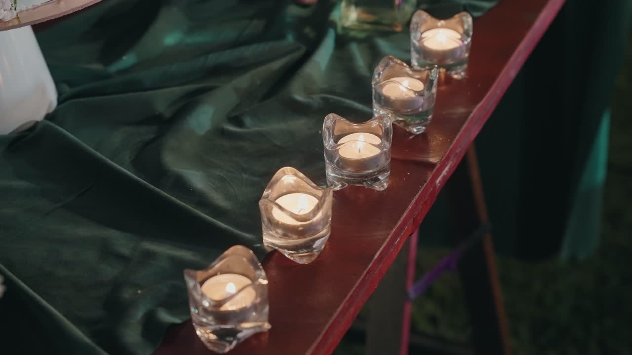 Lit tealight candles in glass holders arranged on elegant fabric table