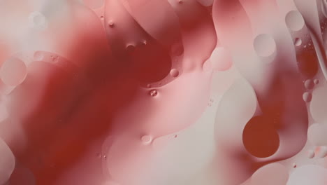 close-up footage of oil flowing across a water surface with a colourful background