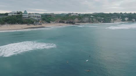 drone de la playa de dreamland, bali, uluwatu indonesia en la hora dorada al atardecer con agua turquesa y surfistas