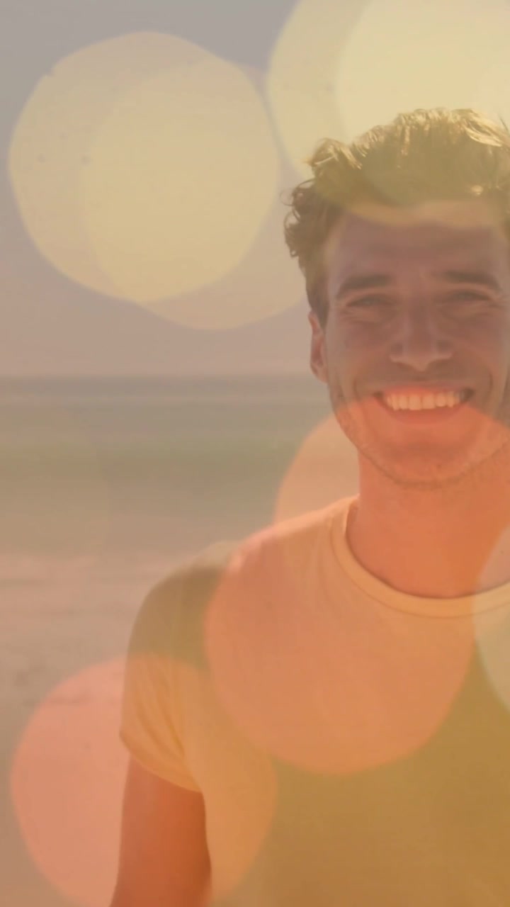 Vertical video: Man posing shore yellow tee sun making bokeh while cam panning smiling for ads