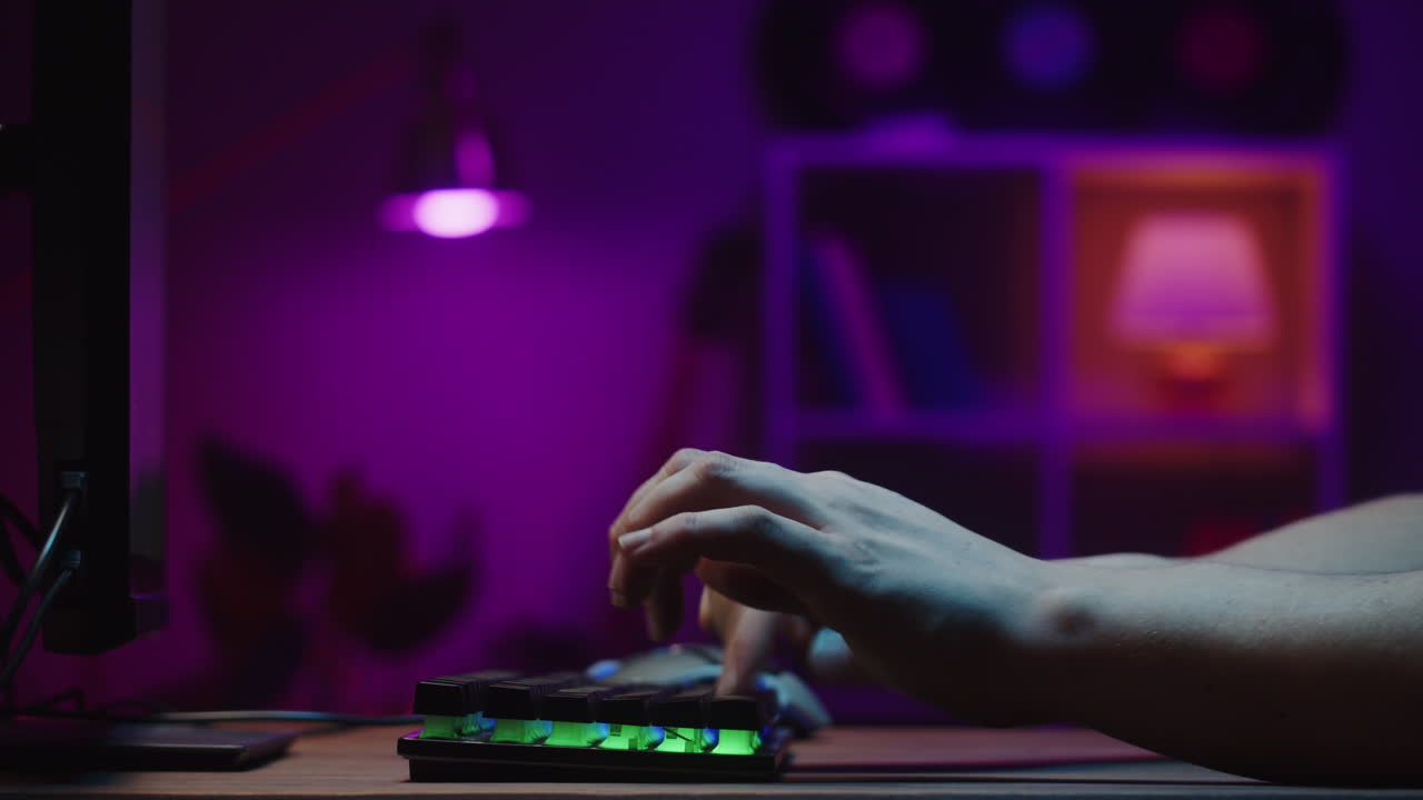Mani che Digitano su una Tastiera da Gaming Retroilluminata in una Stanza Buia